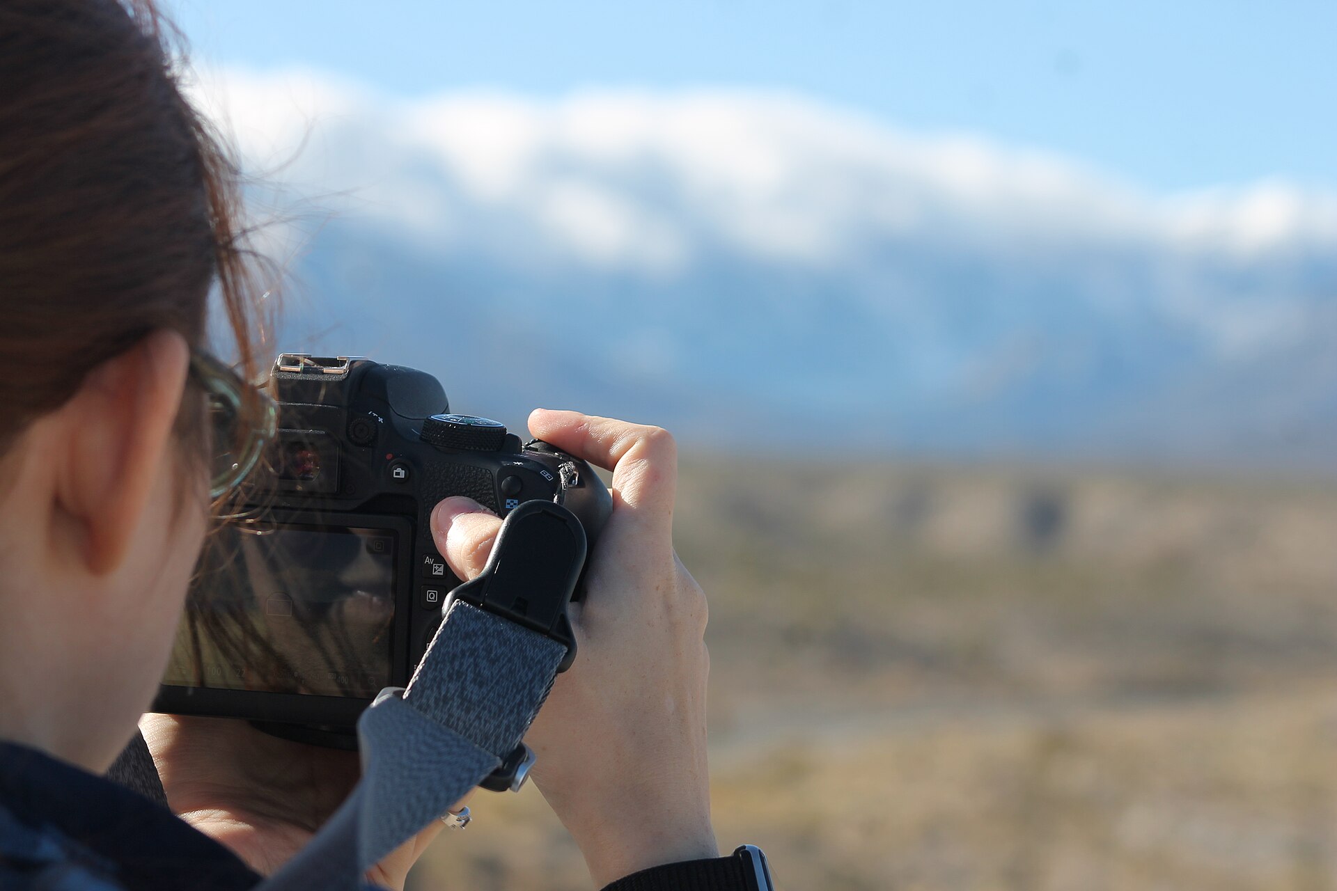 Photographer using a DSLR to capture a mountain landscape — the human expertise that AI photo tools augment, not replace, in Airbnb listing photography.