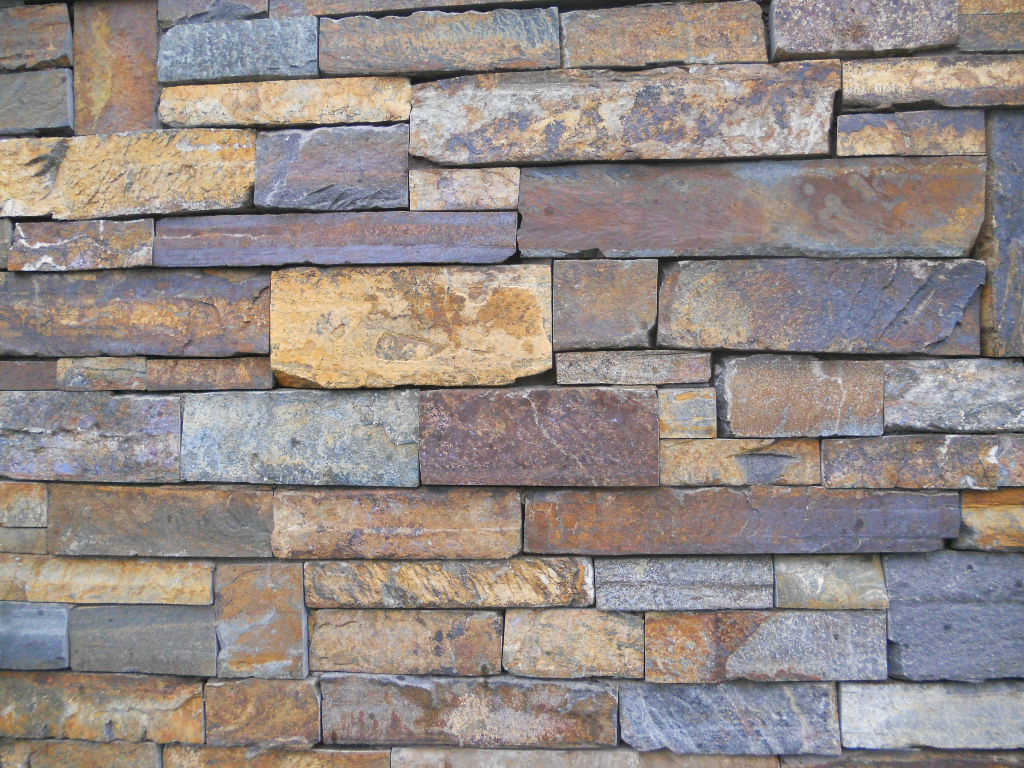 Textured stone-cladding surface — the visual illusion fake surfaces create on a budget, turning a drywall wall into a set-like accent feature.