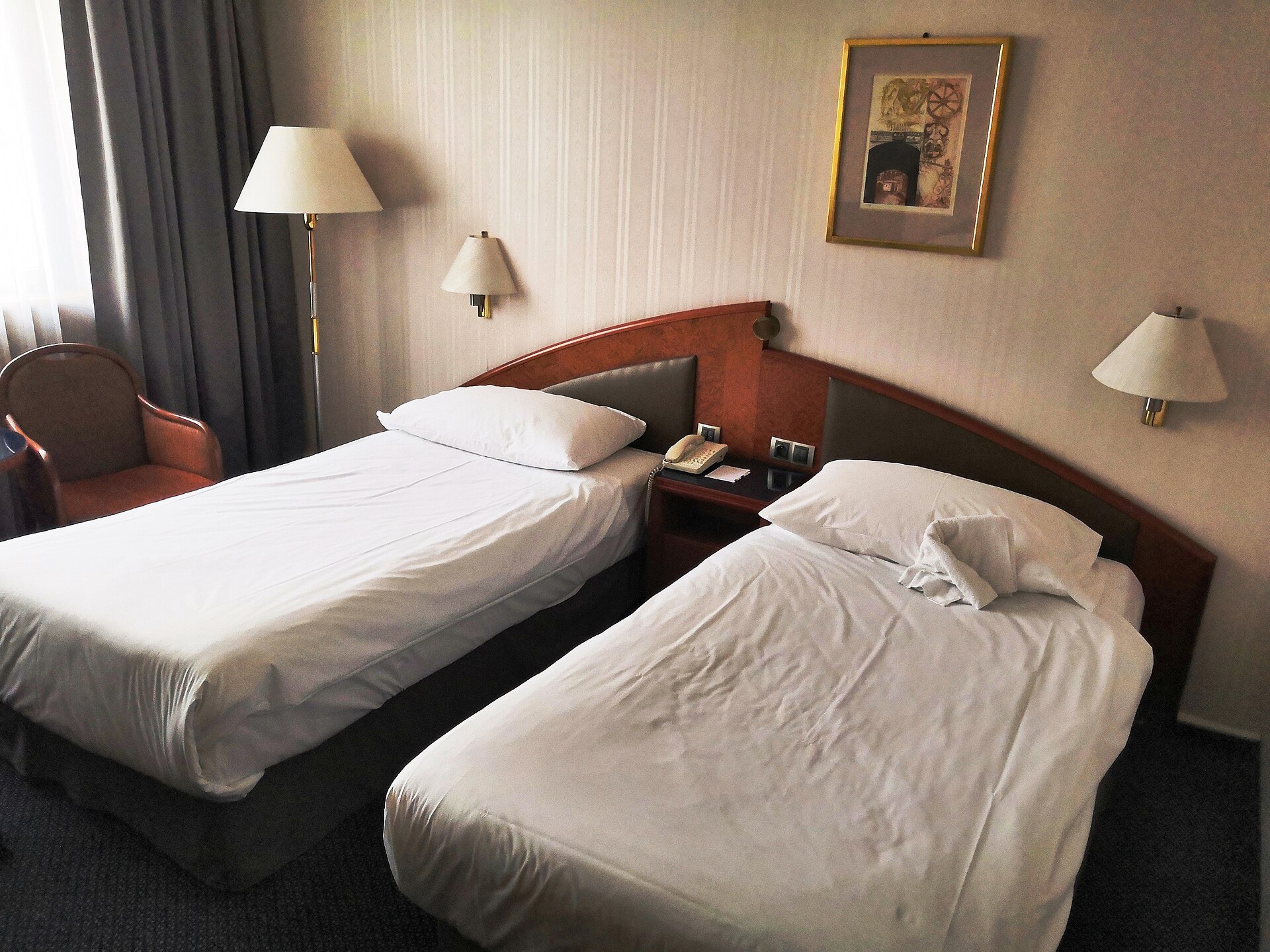 Modern hotel twin-bed room with warm lamps, framed art, and neutral palette — the baseline comfort hierarchy Airbnb guests compare against when rating amenities.